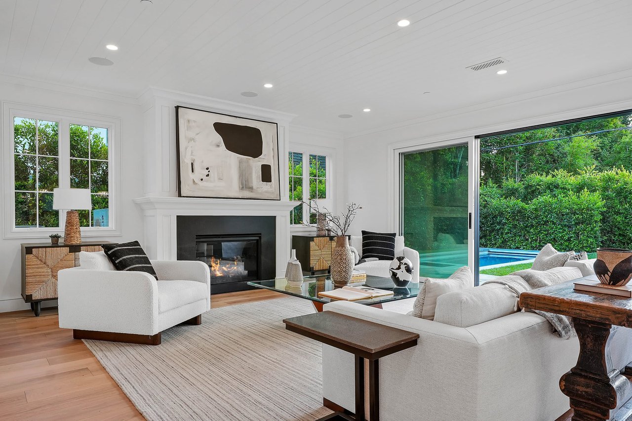  A luxurious and spacious living room with a modern design, featuring a large white sofa and two white armchairs arranged around a glass coffee table.