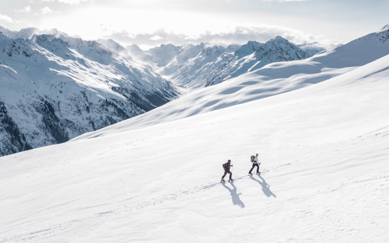 Two snow hikers in the middle of a snowy mountain landscape.
