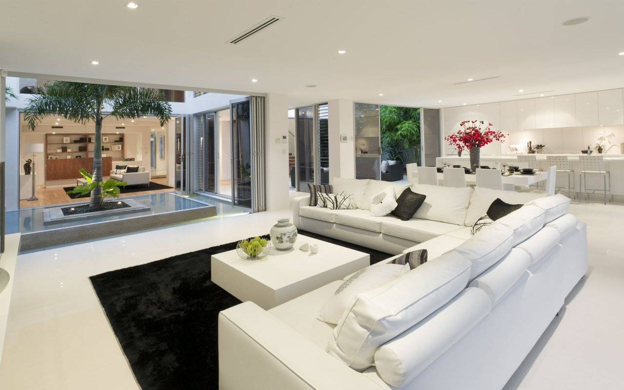 A modern living room with a white couch, a black rug, and a coffee table with a vase on it.