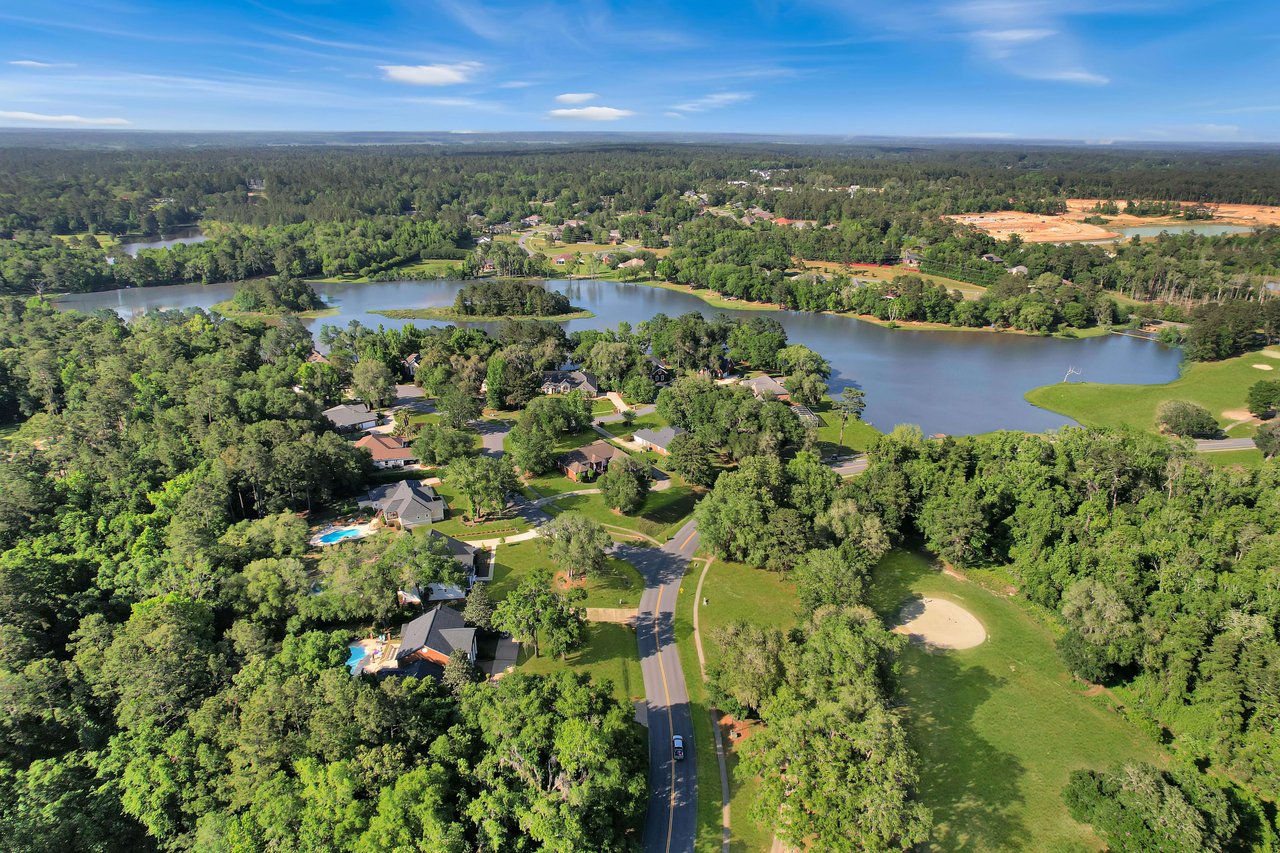 An aerial view of the Summerbrooke community, featuring houses, a golf course, and a lake surrounded by greenery.