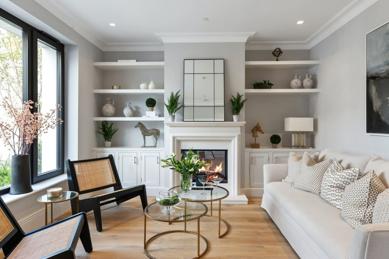 A living room with a fireplace, a couch, two chairs, a coffee table, and a window.