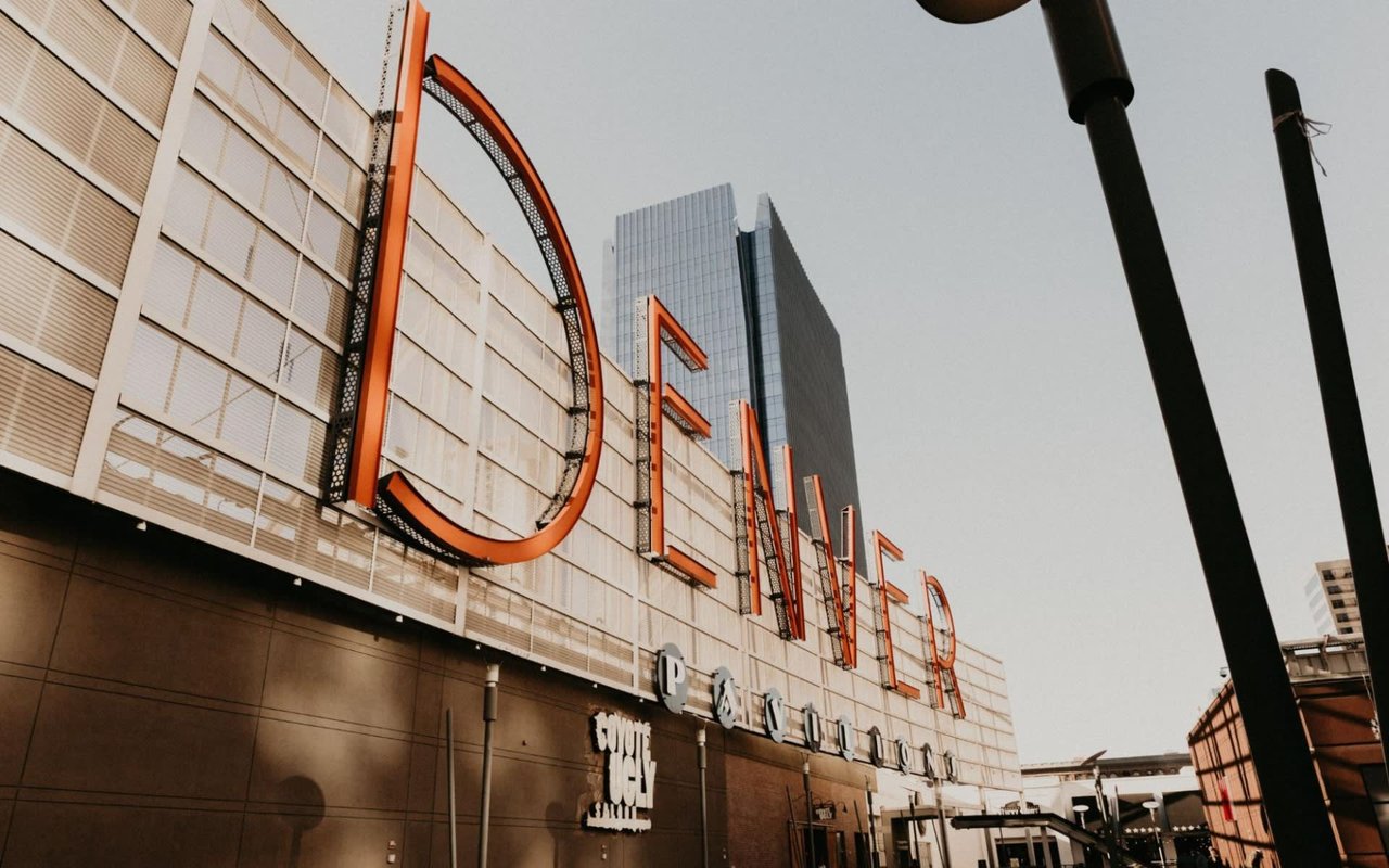 The building's facade is made of light-colored panels or glass, and some smaller text is visible below the large "DENVER" sign