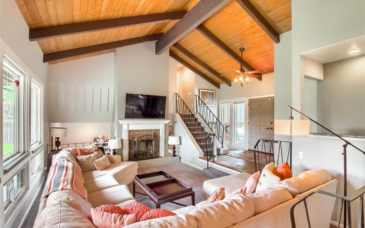  A modern and bright living room features a large, L-shaped light-colored sectional sofa with decorative pillows, including a striped one and another with a dotted pattern.