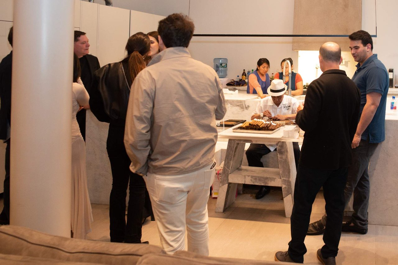 Guests watch a chef present cigars at an indoor gathering.