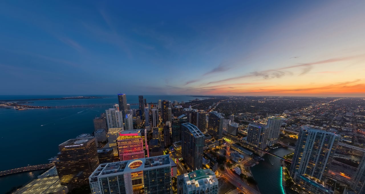 Aerial view of downtown high-rises beside the water at sunset.