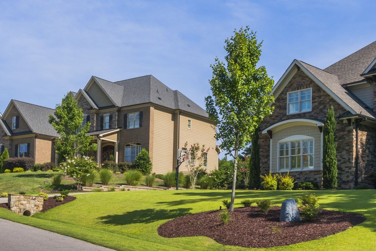 A row of houses in a suburban neighborhood. The houses have the same colors and styles and are all well-maintained.