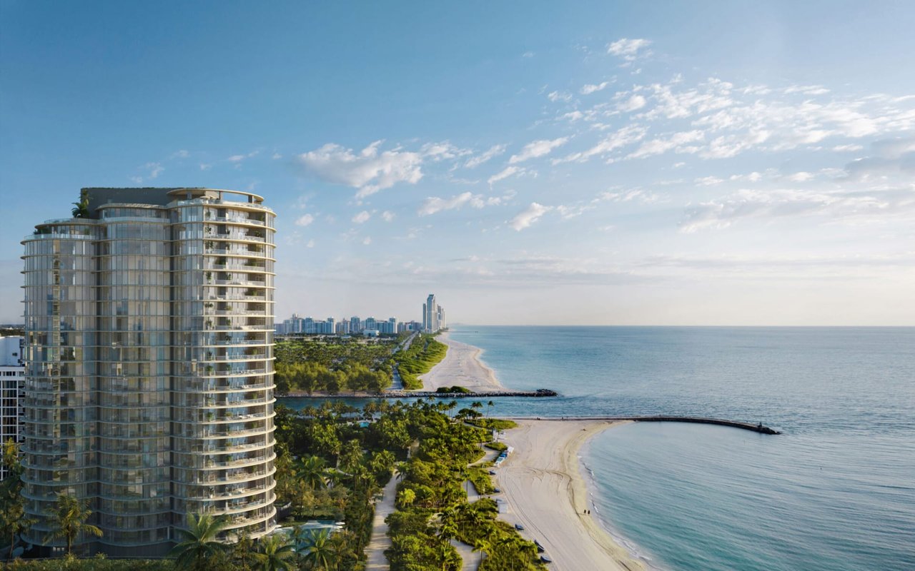 Curved glass residential tower overlooking a palm-lined beach and ocean.