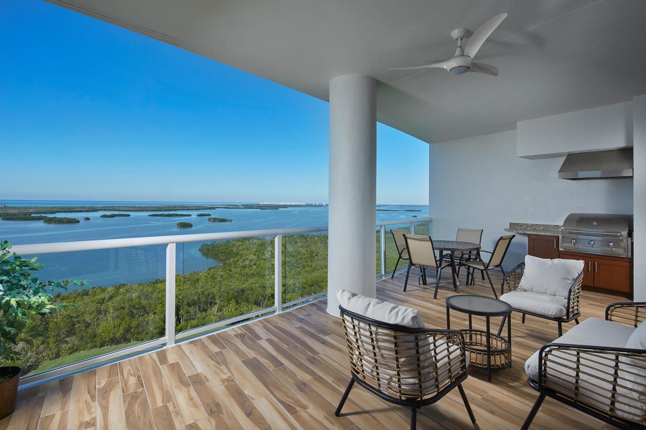 A wide shot of a balcony featuring a seating area with a small round table and four chairs.
