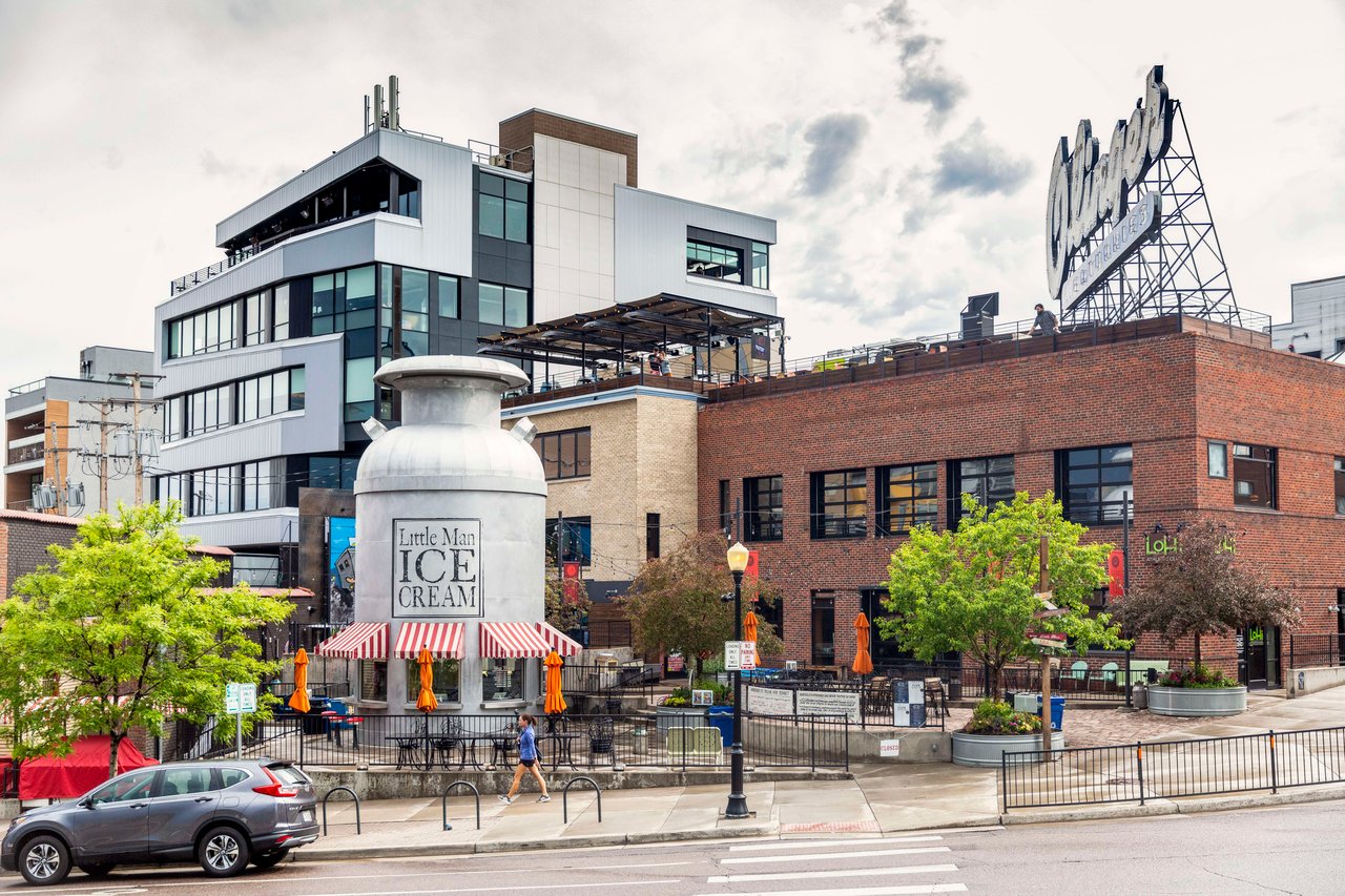 A giant ice cream bottle in front of a building in a city.