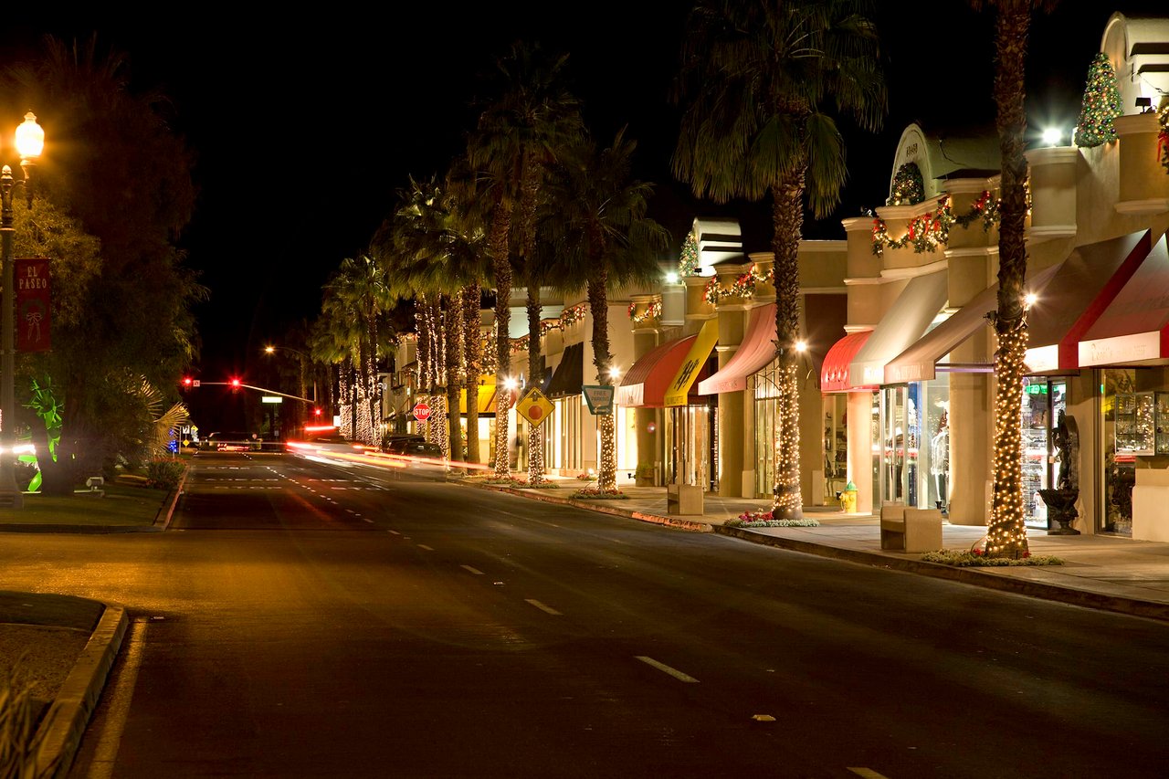 A bustling nighttime scene on a palm-lined avenue