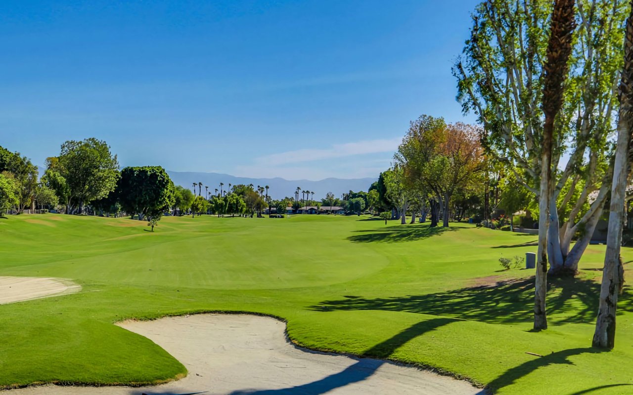 A golf course fairway with a sand trap on the right side