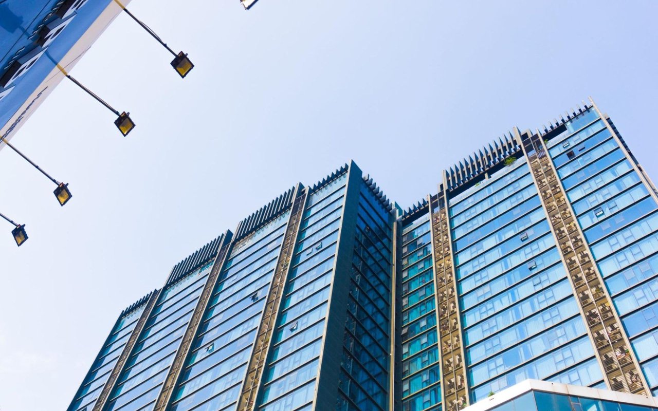  A low-angle view of a modern skyscraper with a blue glass facade and numerous windows