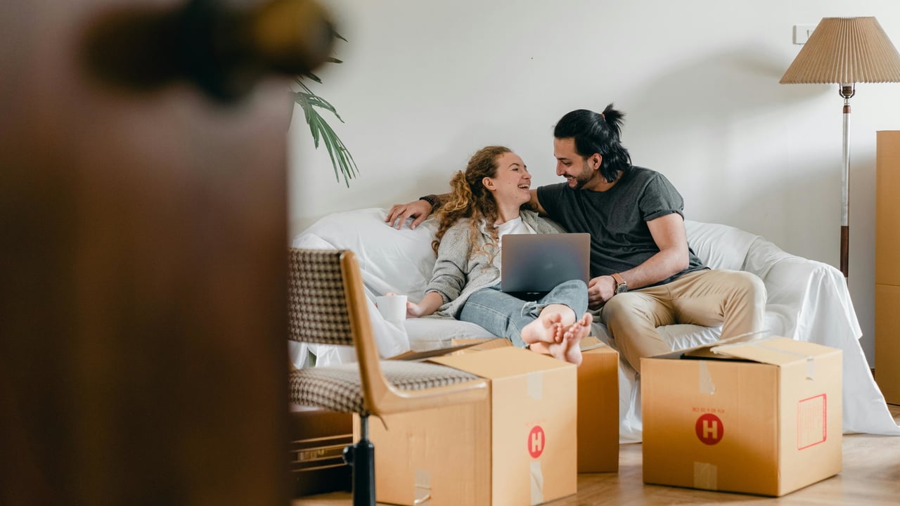 A couple sitting on a couch and looking at a laptop after packing for moving to Florida