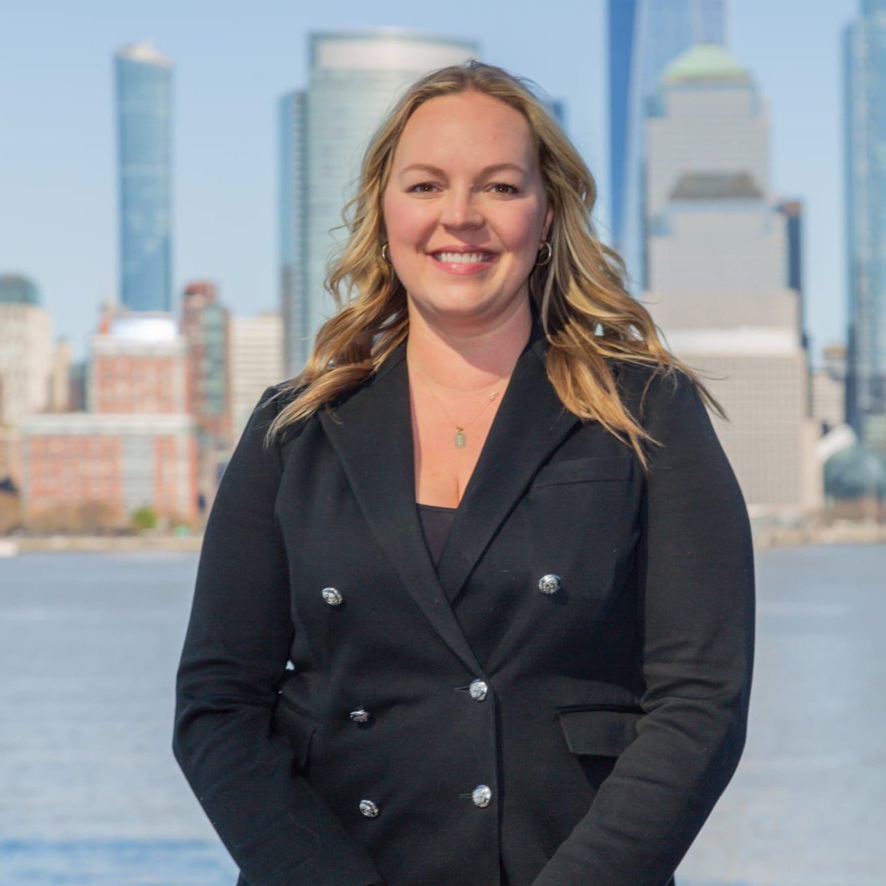 Johanna Fine, a real estate professional in a suit, standing in front of a picturesque city skyline.