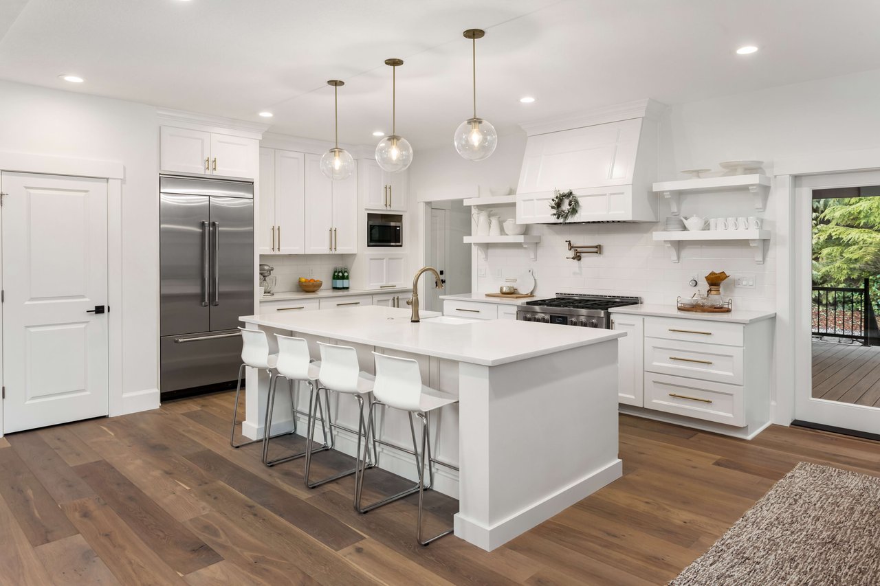 Picture of a renovated chef's kitchen with white counter tops and stainless steel appliances