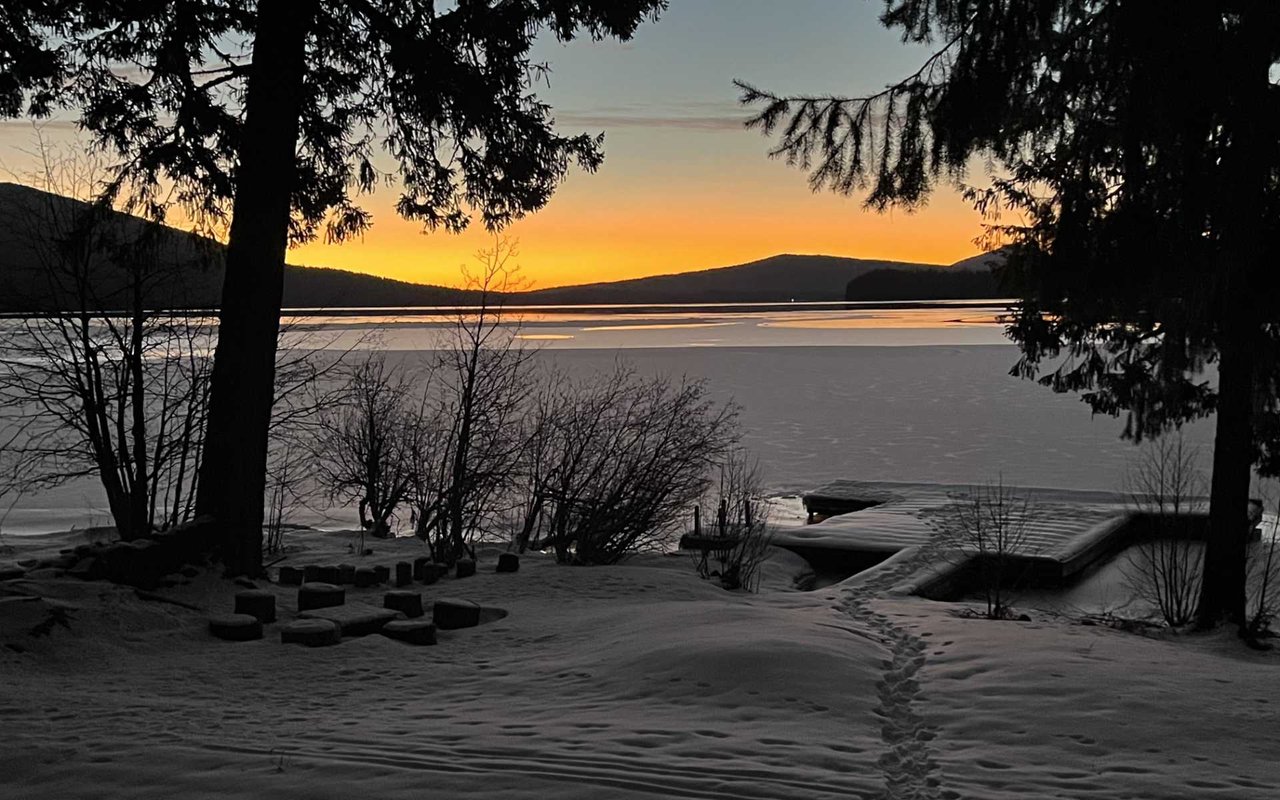 stunning sunrise by the snowy lake surrounded by mountain ranges