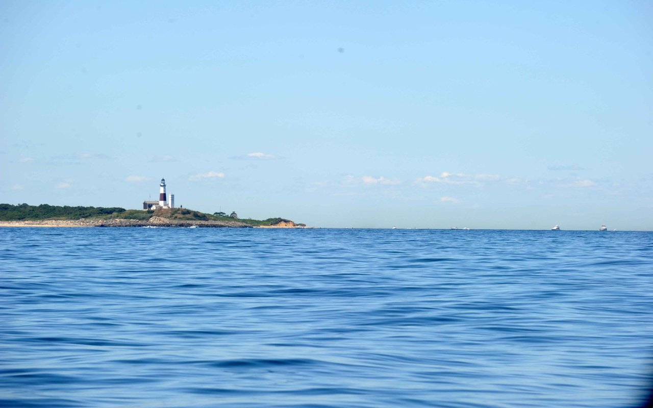 A tall, white lighthouse on a tiny, rocky island surrounded by the vast ocean.