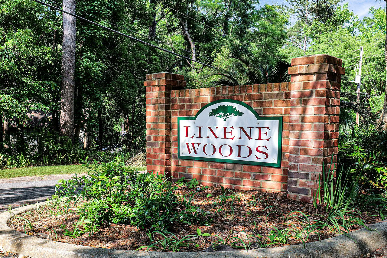 A ground-level view of the entrance sign for "Linene Woods," indicating the name of the residential community.