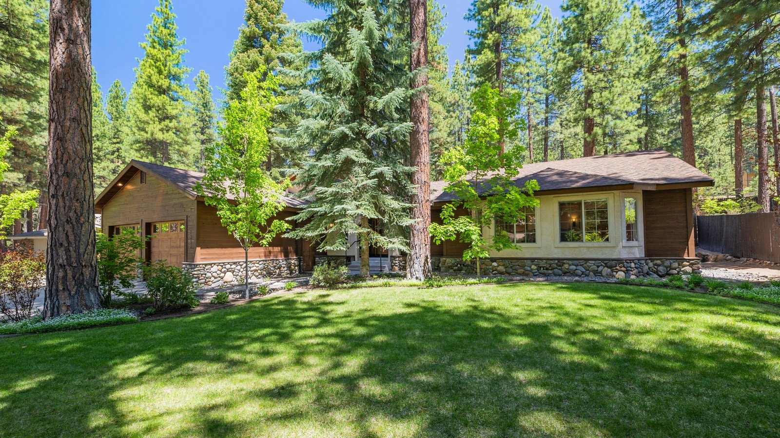 Single-story wood and river-rock home with a wide, level lawn under tall pines at 1052 Sawmill Road in Mill Creek, Incline Village