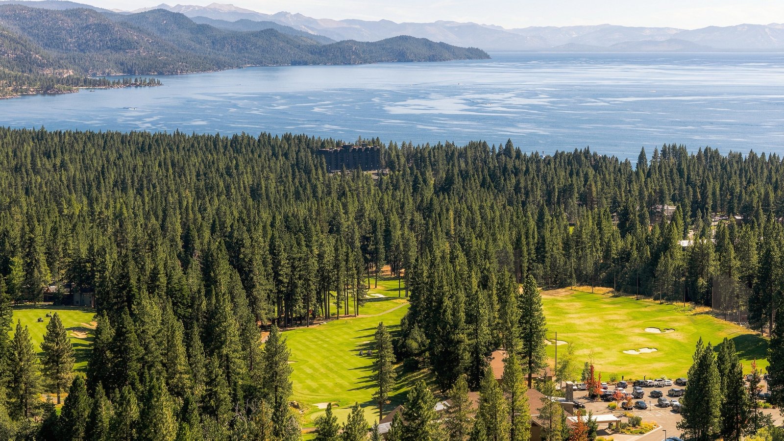 Aerial view of the Championship Golf Course in Incline Village, Nevada, with fairways cut through tall pines and Lake Tahoe beyond