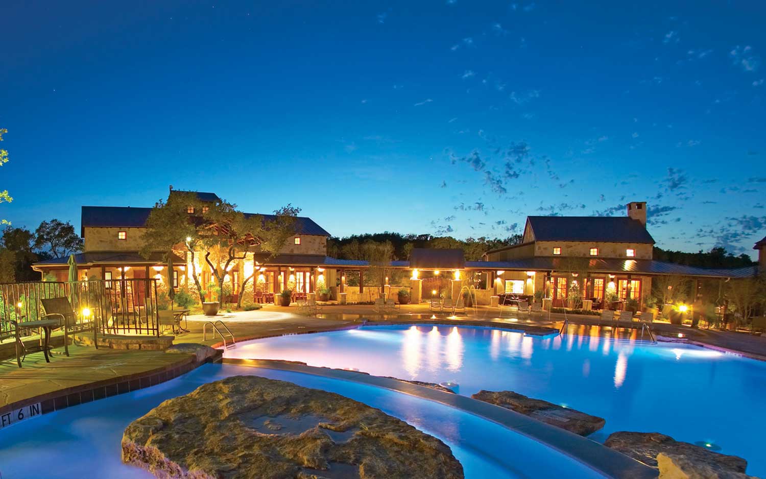 Austin-area luxury estate at dusk with a lit pool and glass walls