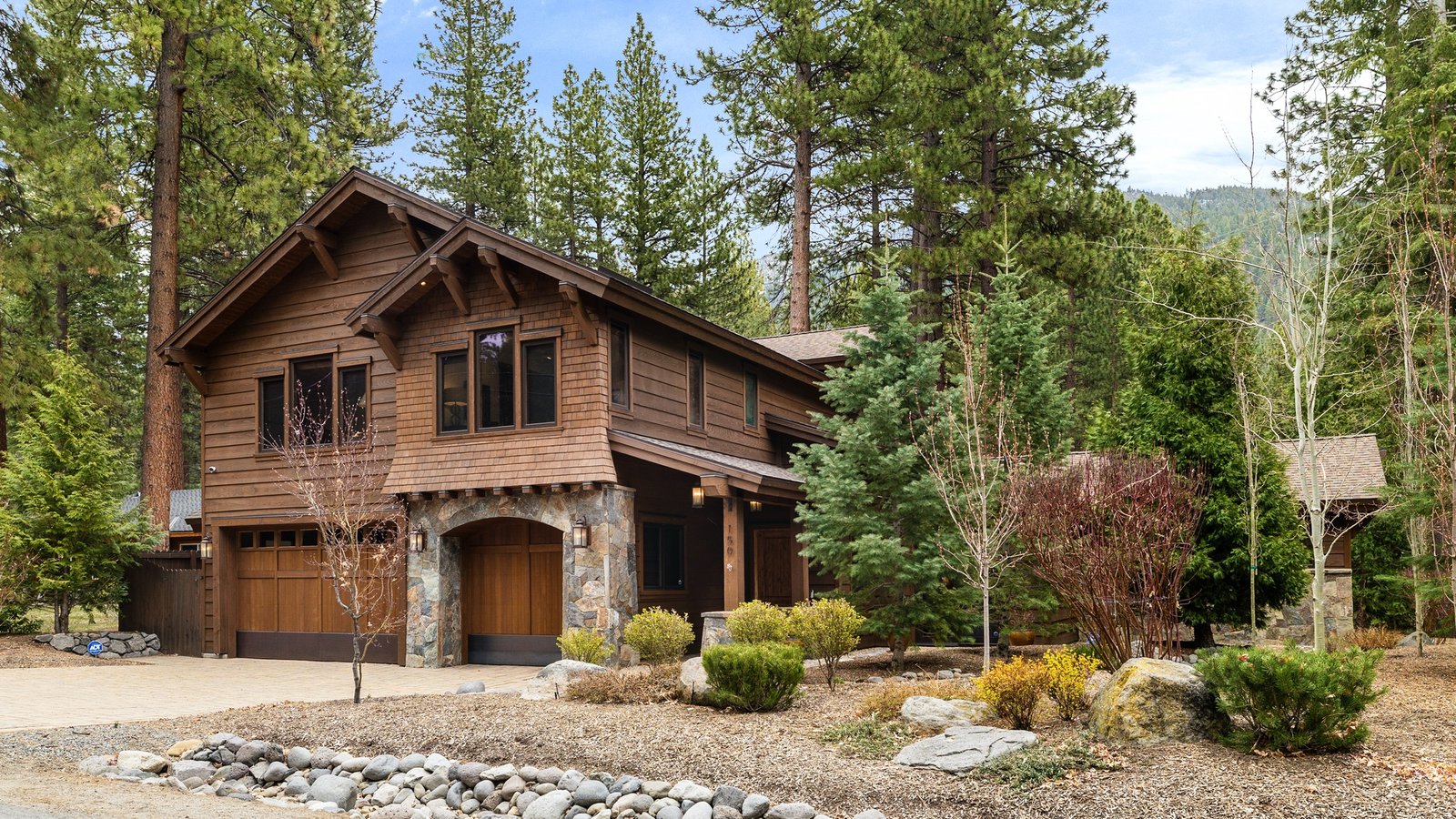 Two-story shingle-sided mountain home with stone-arched garage doors among the pines at 150 Pine Cone Road in Mill Creek, Incline Village