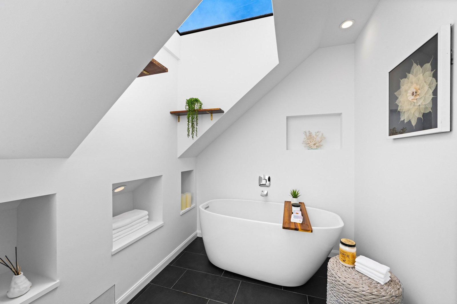 Freestanding soaking tub beneath a skylight in the primary bath at 449 Frederick Street