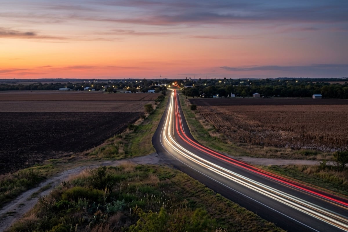 Road through flat farm fields at dusk, the open country between the north Austin suburbs and Taylor