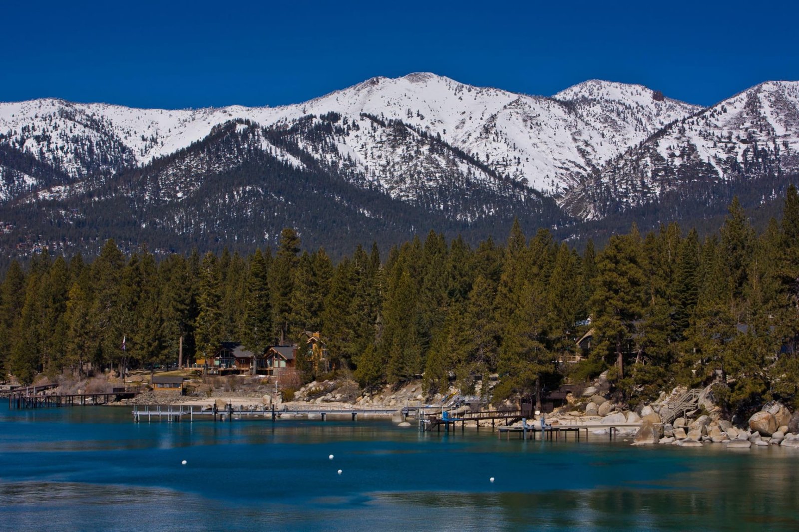 Lake Tahoe shoreline with turquoise water and docks below snow-covered mountains