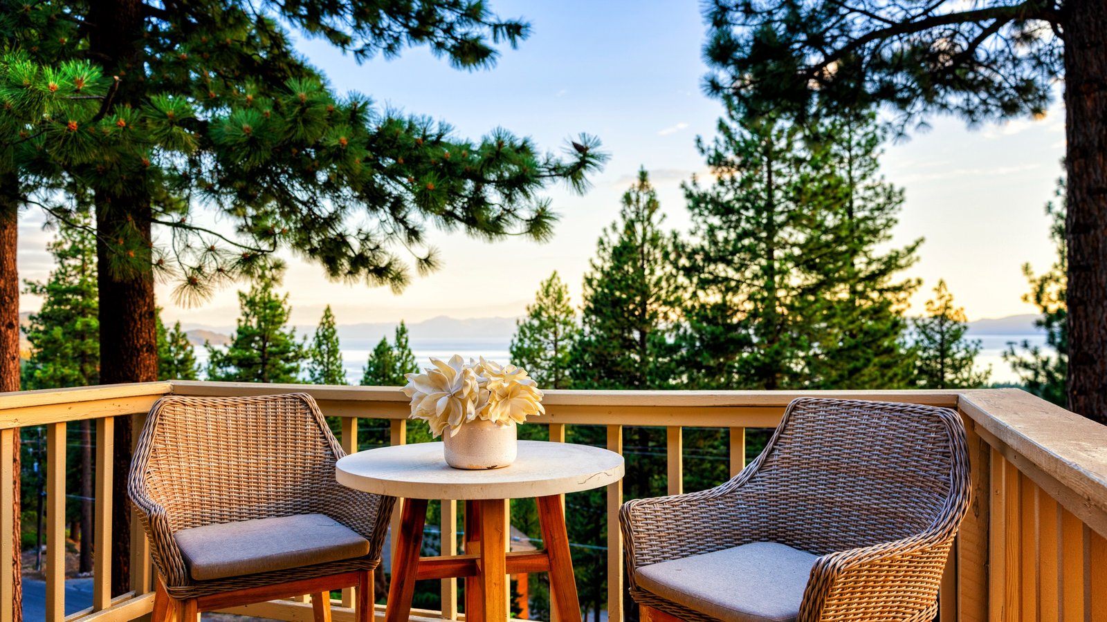 Deck with two chairs at a 400 Fairview Boulevard condominium in Incline Village, looking through the pines to Lake Tahoe