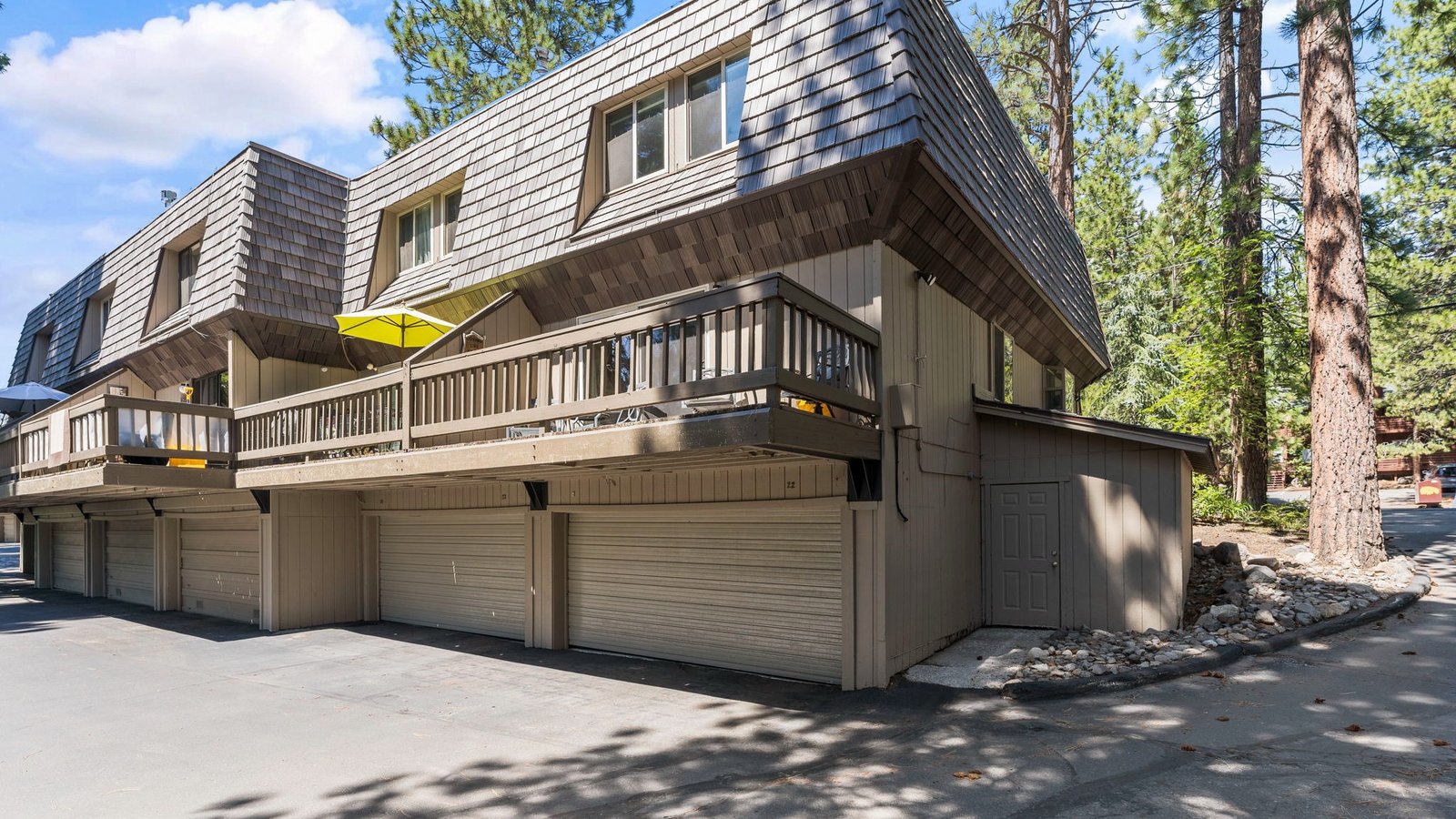 Two-story condominium building with balconies above a row of garages, set among tall pines on Southwood Boulevard