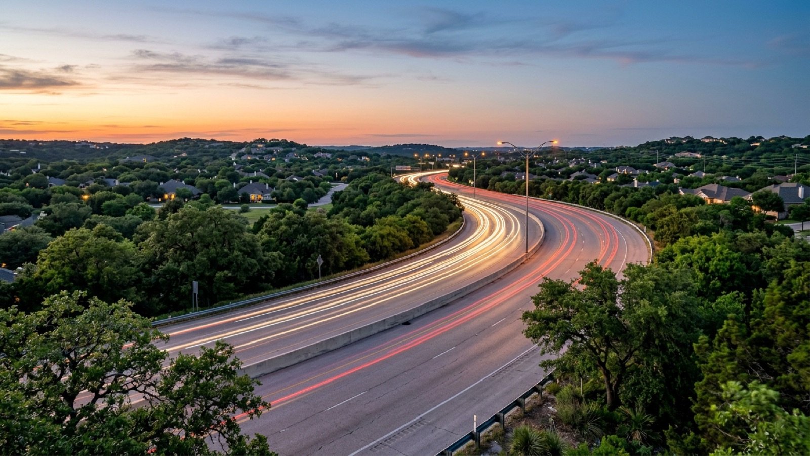 A divided highway through green north Austin suburbs at dusk, for testing a commute before buying