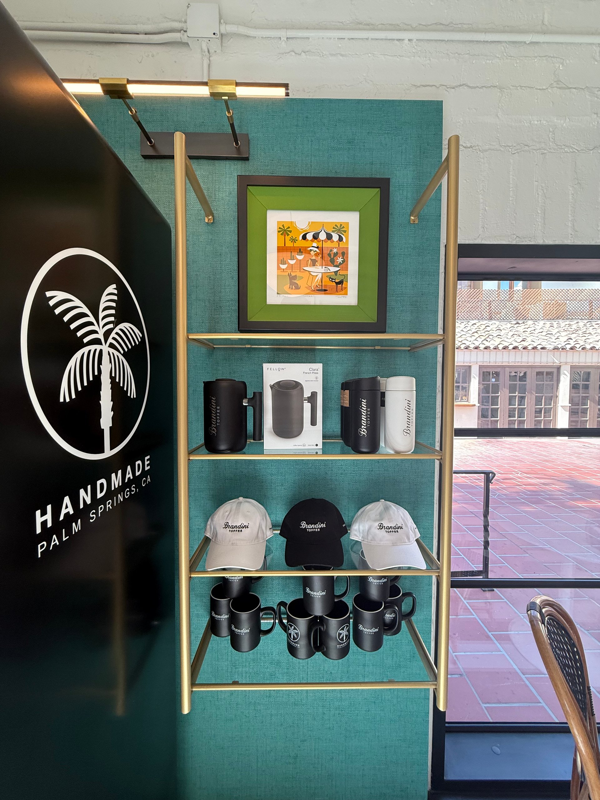 Brandini Toffee merchandise beside a Handmade Palm Springs wall graphic