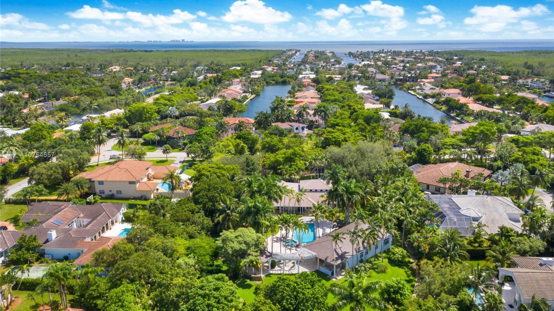 Aerial view of Pinecrest Miami waterfront homes with pools and canal access - The Edit Real Estate