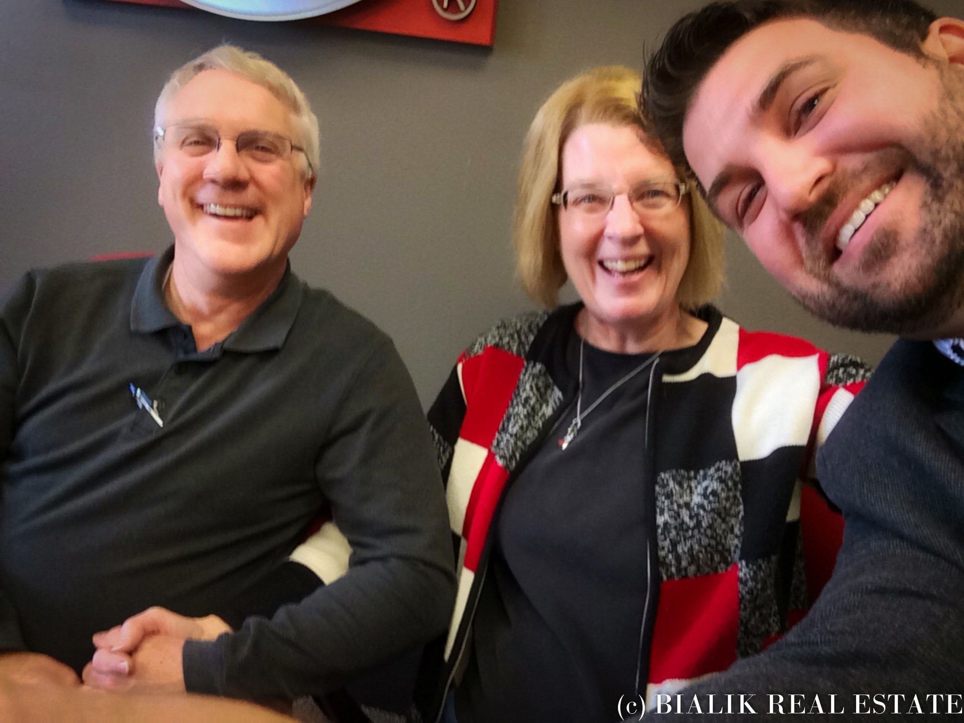 Bruce and Jody smile with their real estate agent in a close-up closing-day selfie.