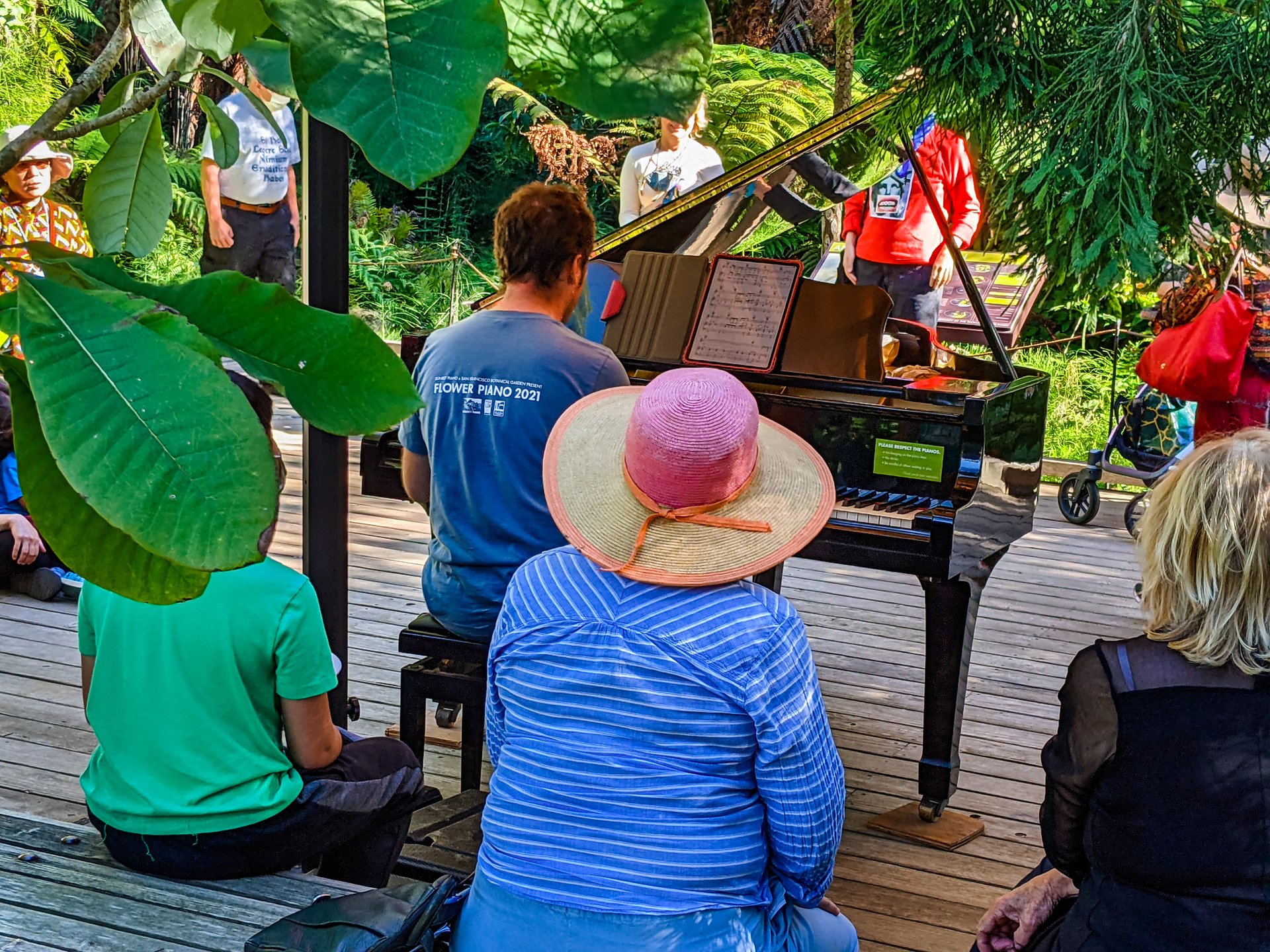 People listening to a piano performance in a botanical garden