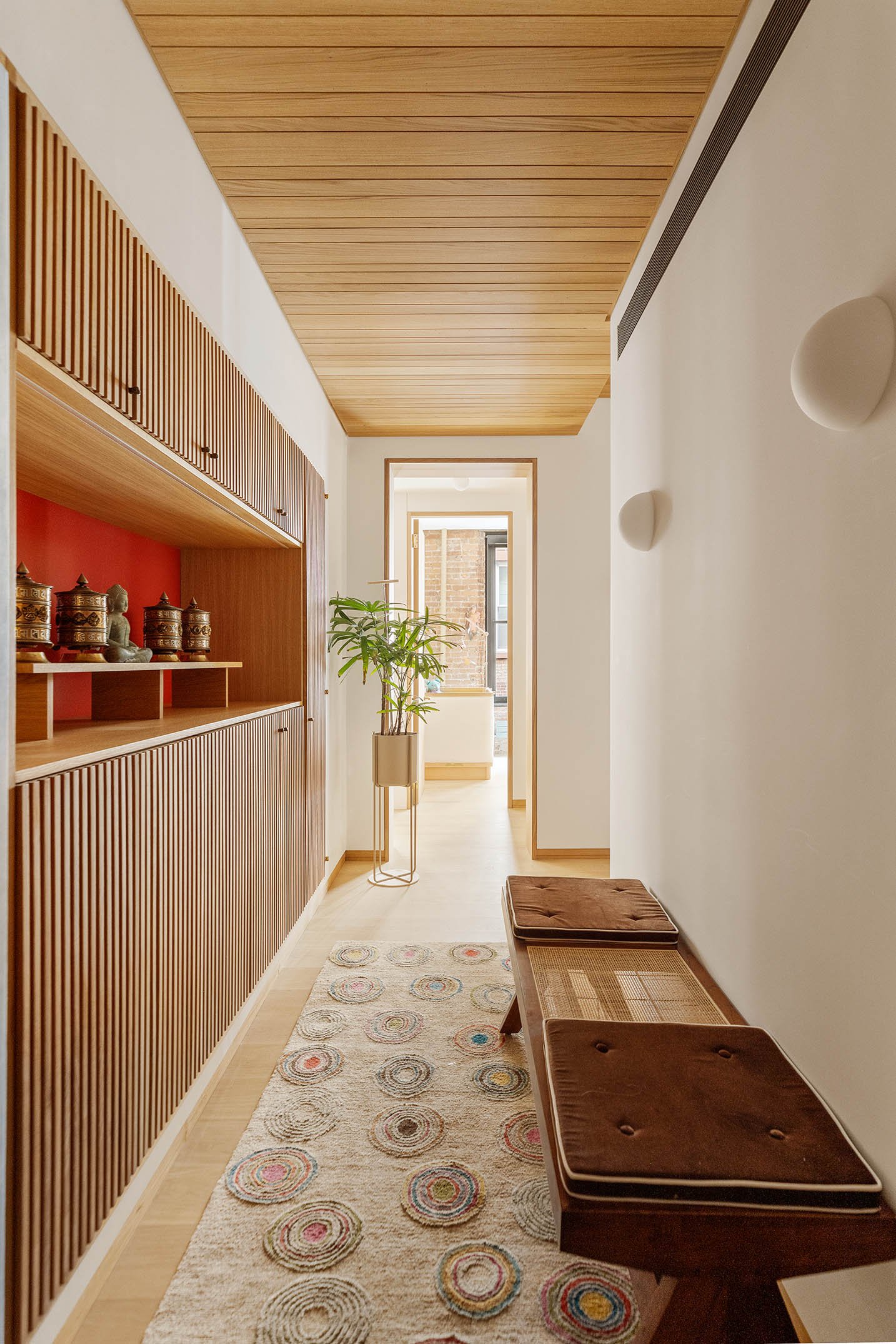 Oak-lined passage at 50 Wooster Street 4NR, with integrated storage, a bench and daylight at the far end.