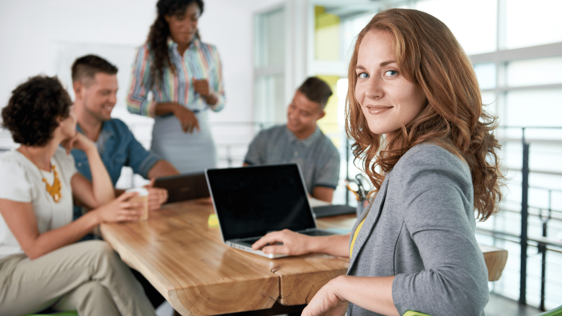 Business professionals meeting at conference table with laptop in Miami office - The Edit Real Estate Miami corporate team relocation services