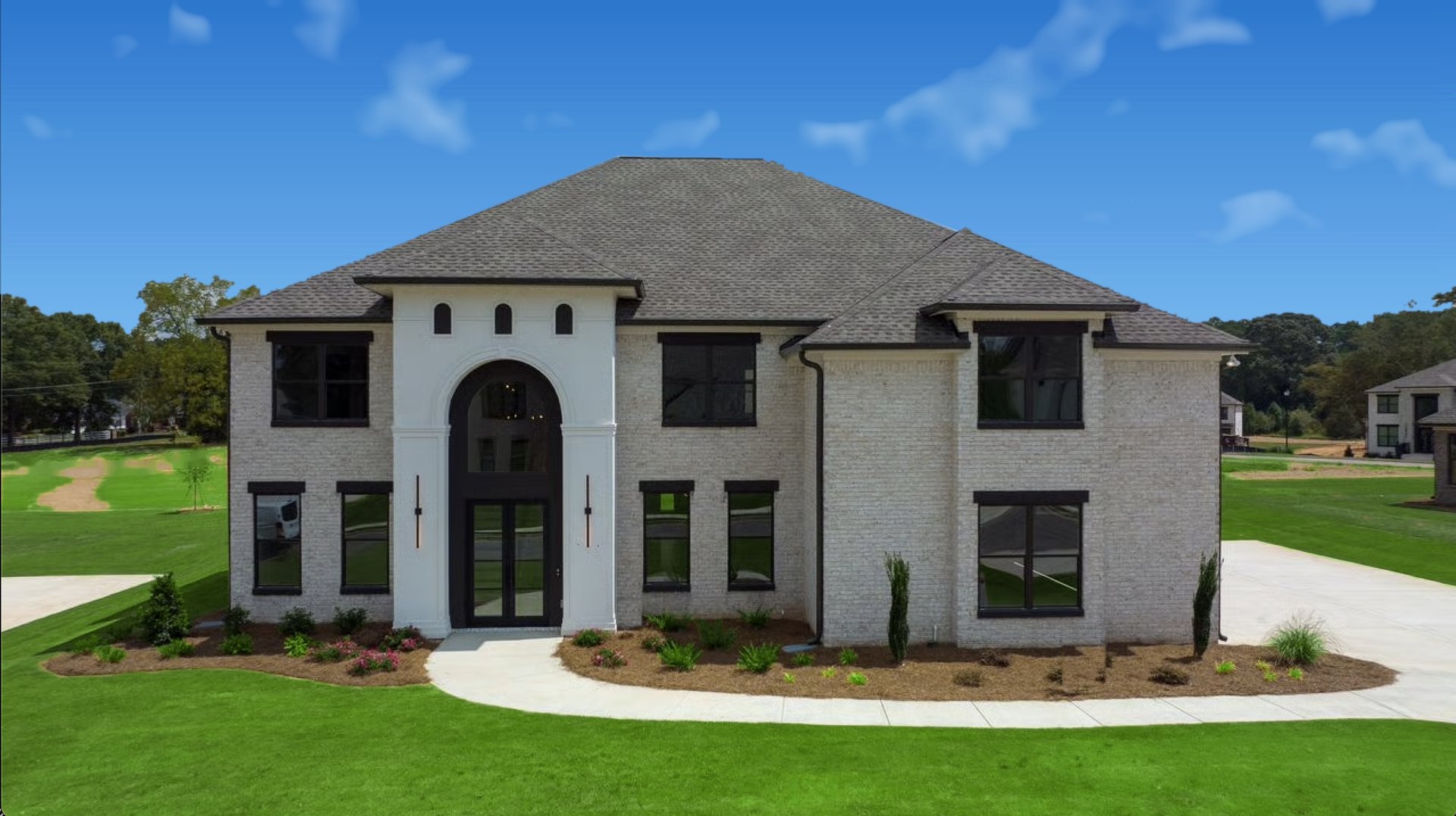 Two-story white brick house with a prominent arched entry and landscaped lawn.