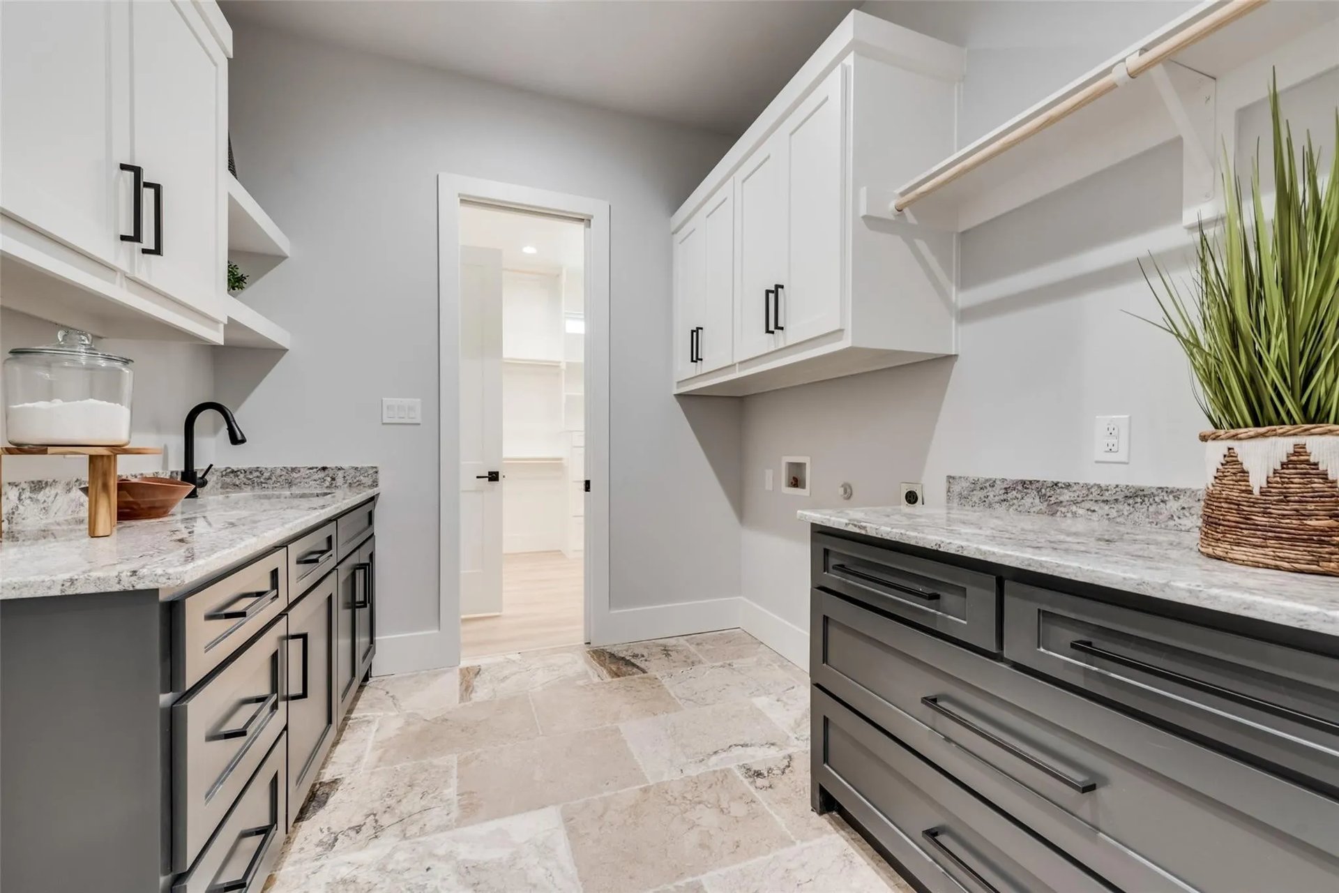 Laundry room with gray drawers, stone counters, white cabinets, and a hanging rod.