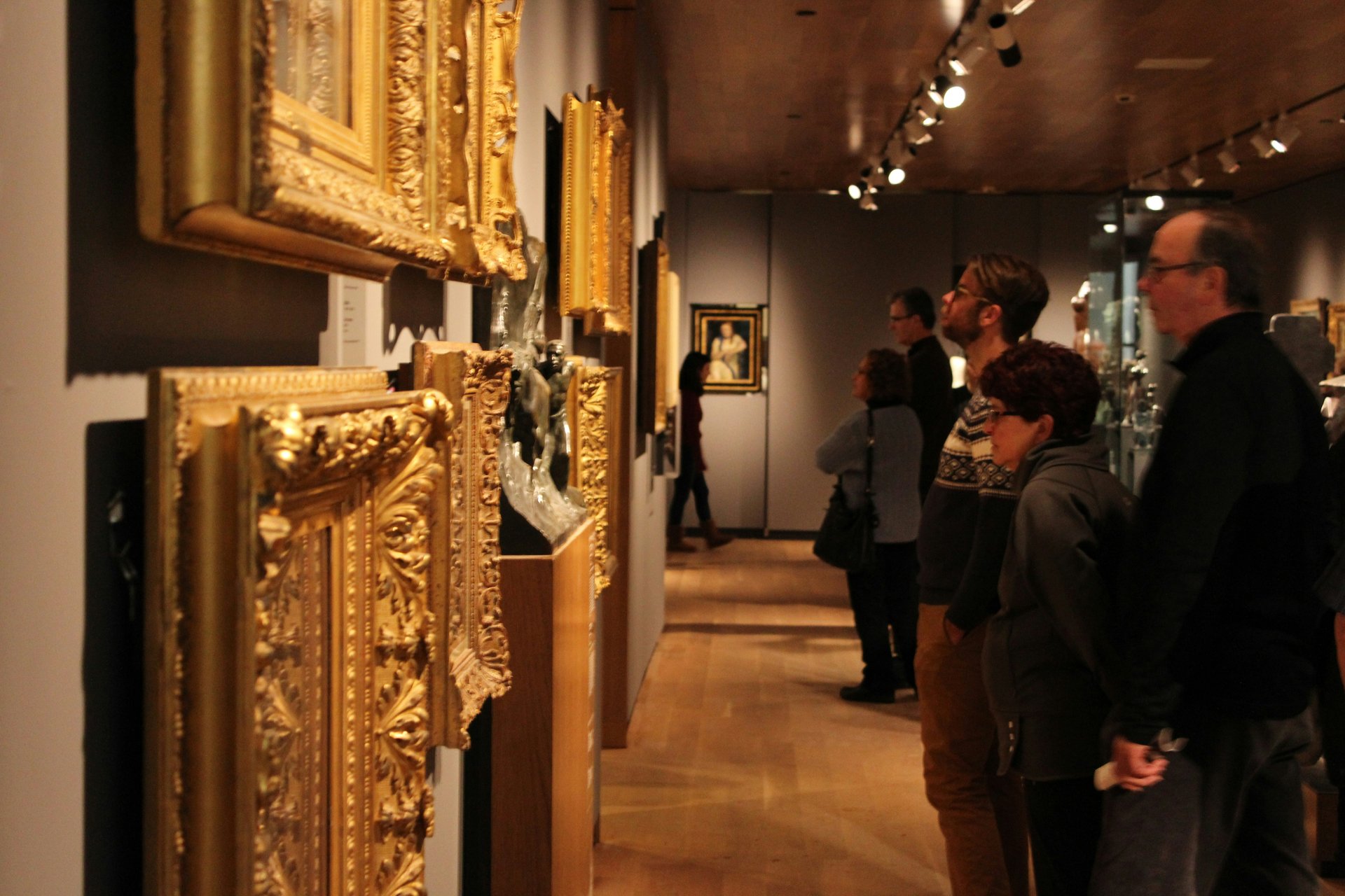 Visitors examining artwork and decorative objects in a gallery