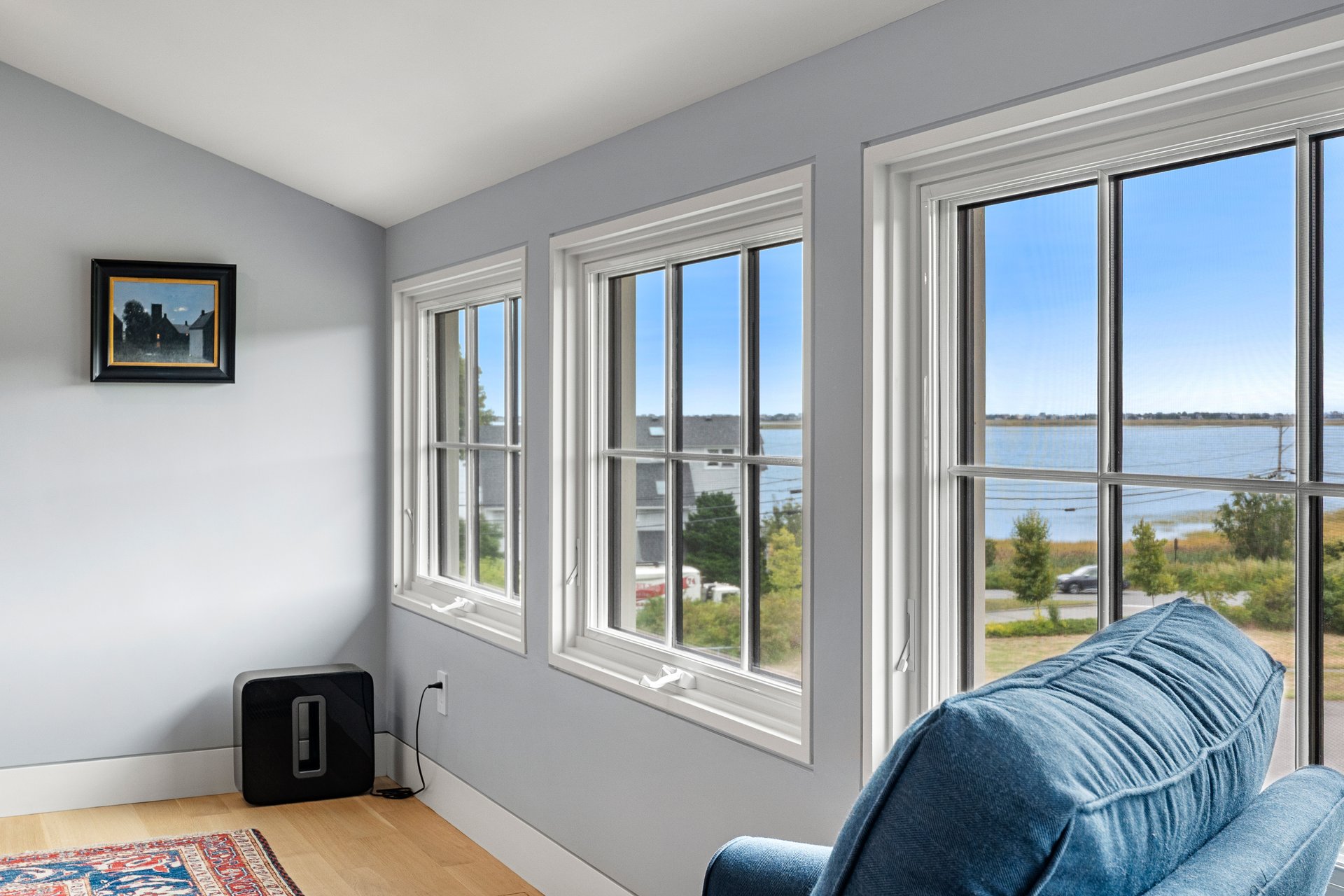 Sitting area with blue sofa and large windows overlooking the water.