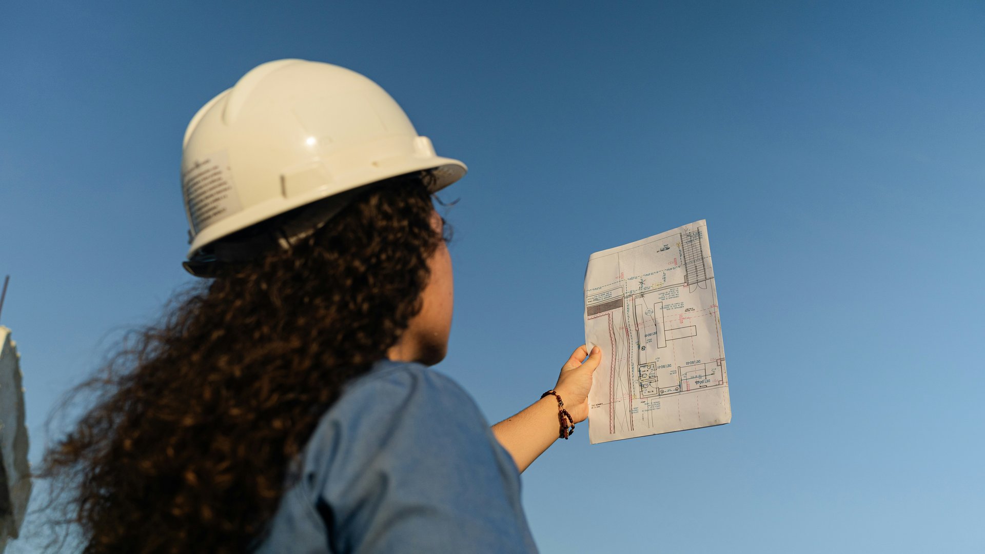 Person reviewing architectural plans while evaluating a home