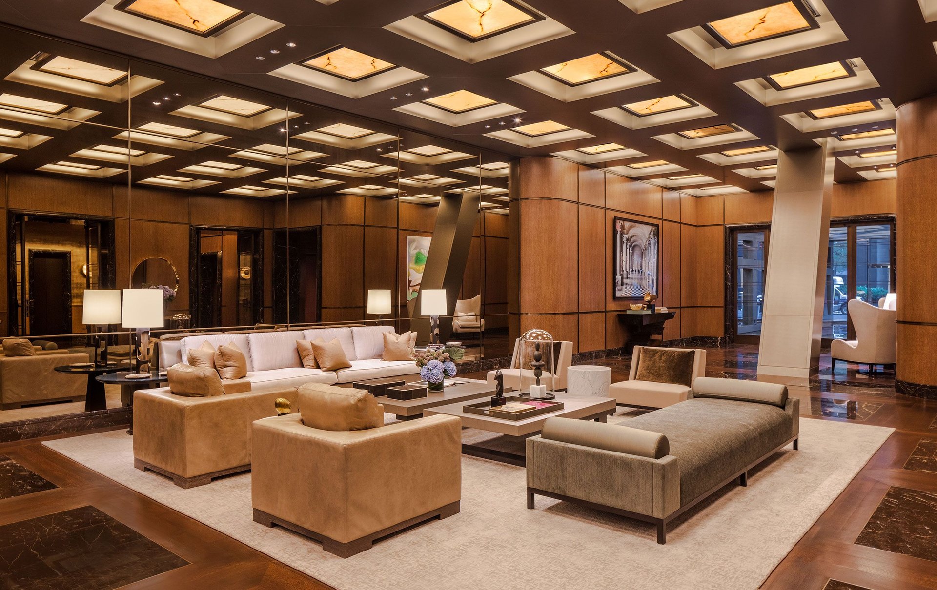 Residential lobby with lounge seating, wood-paneled walls, and a geometric illuminated ceiling.