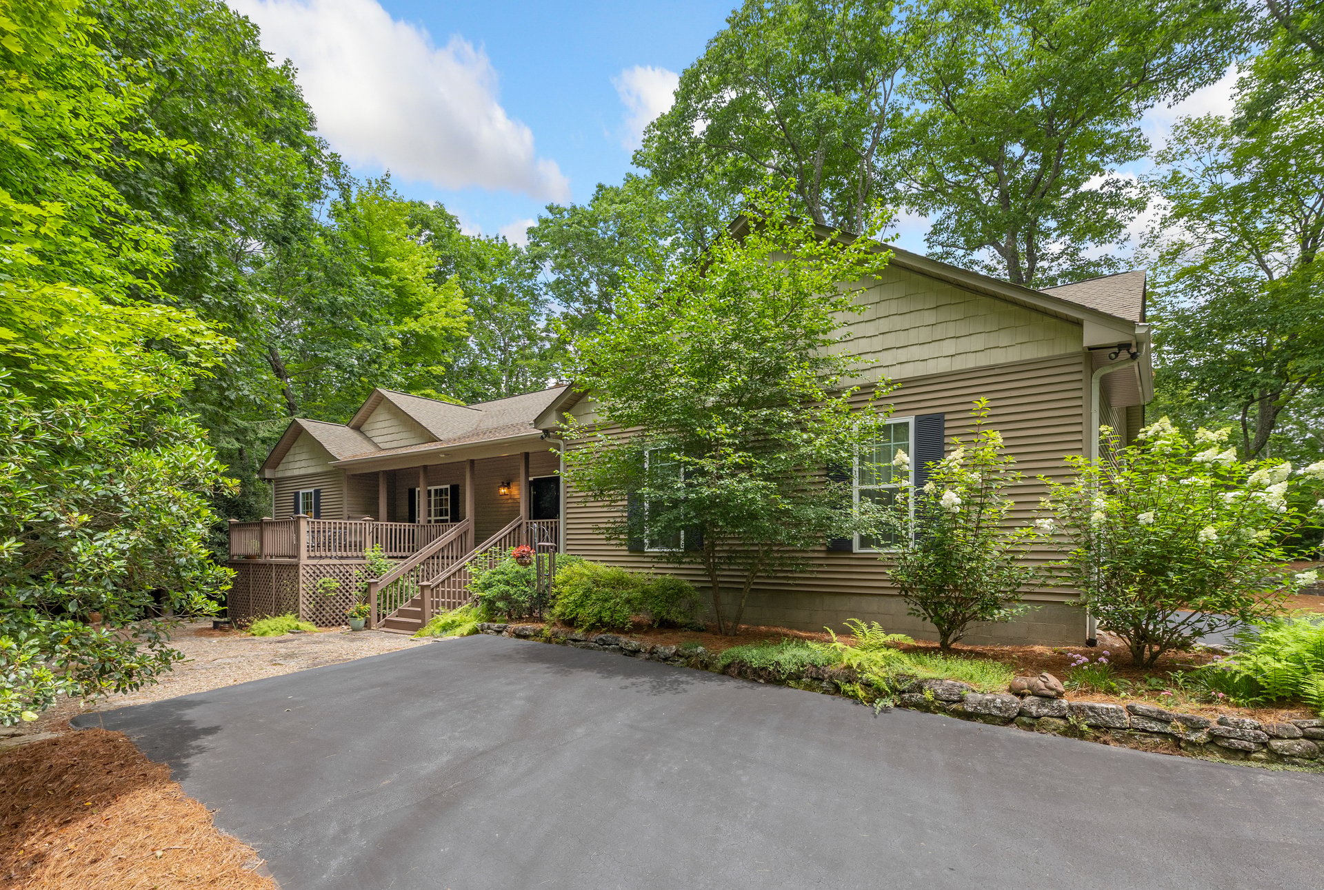 Ranch-style home with a covered front porch, landscaped beds and paved driveway at 141 Dolly Lane, Highlands NC