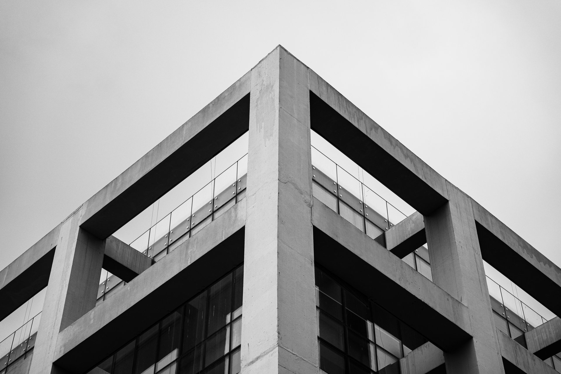 Modern commercial building with a geometric concrete frame and glass windows, photographed from below.