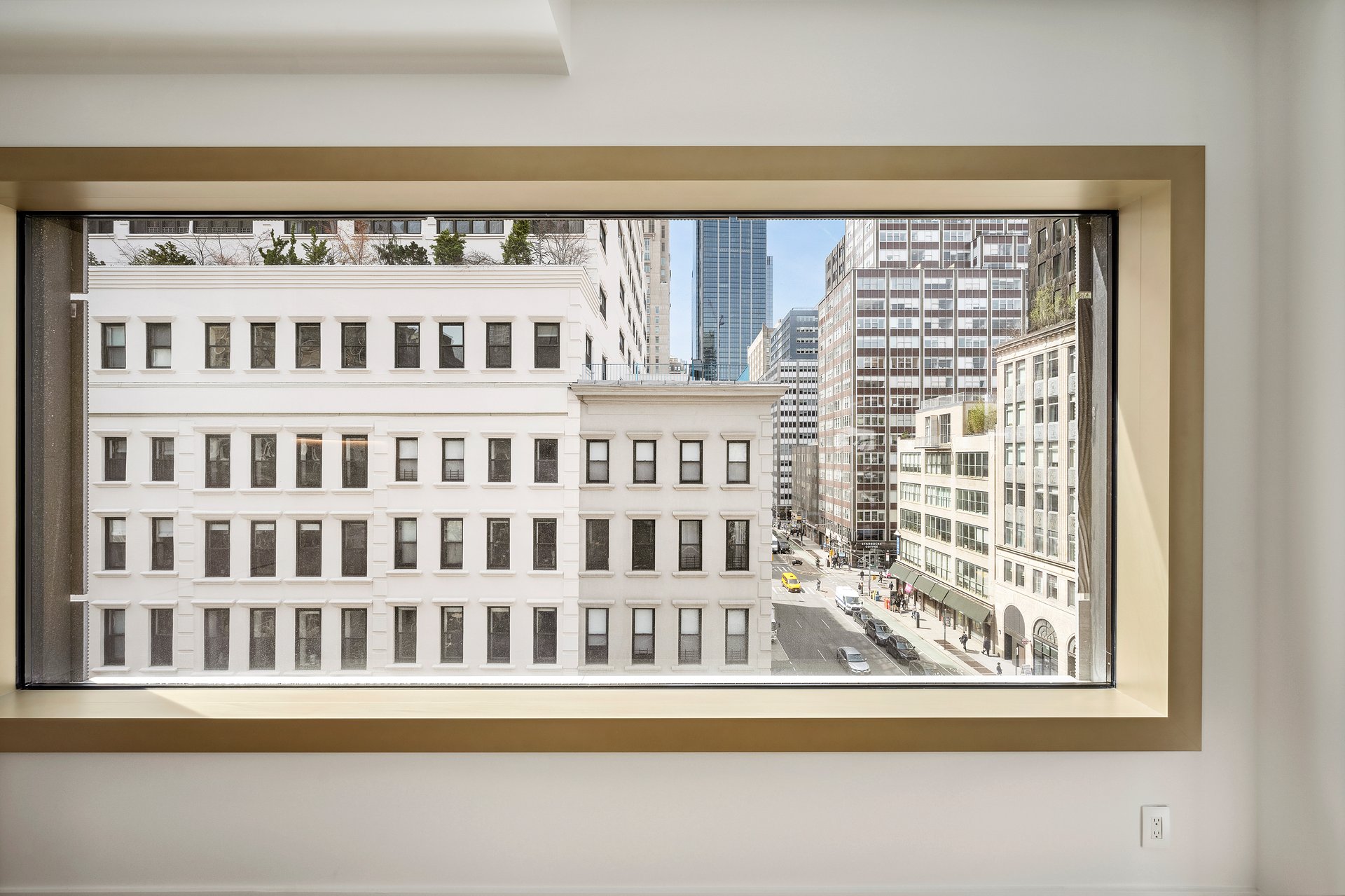 Large apartment window framing downtown buildings and a Manhattan street.
