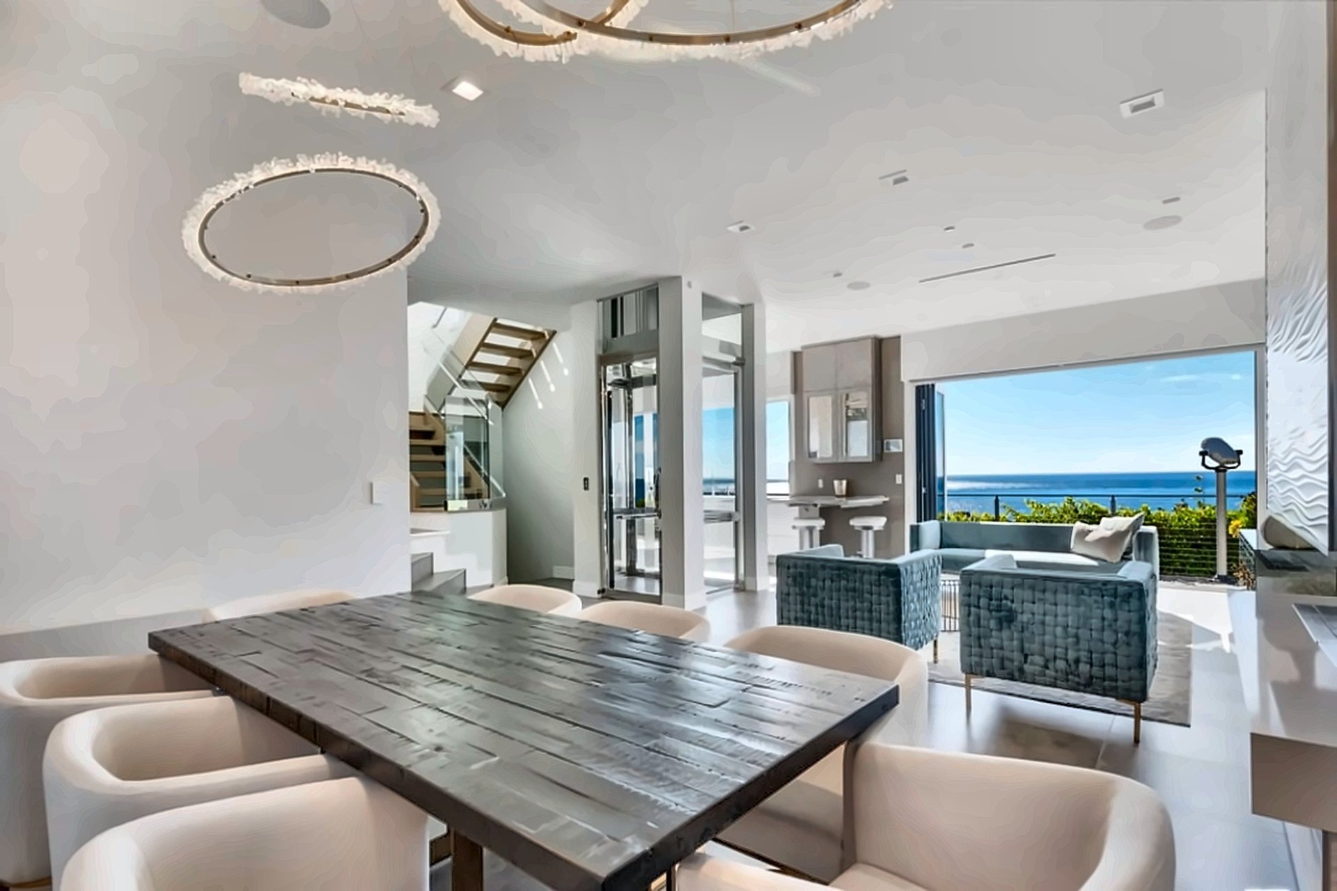 Dining room opening to the ocean through walls of glass in a Malibu home