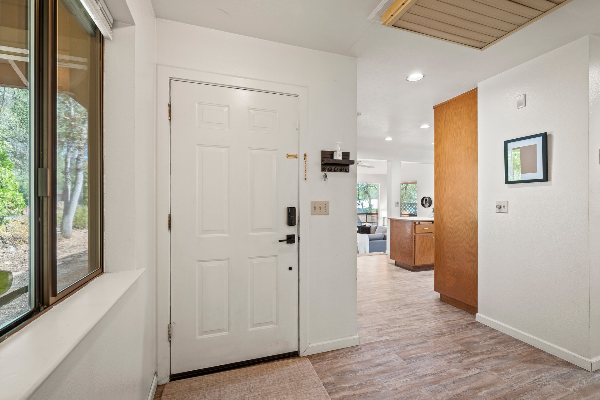 Home entryway with a white paneled door, large window, and wood cabinetry.