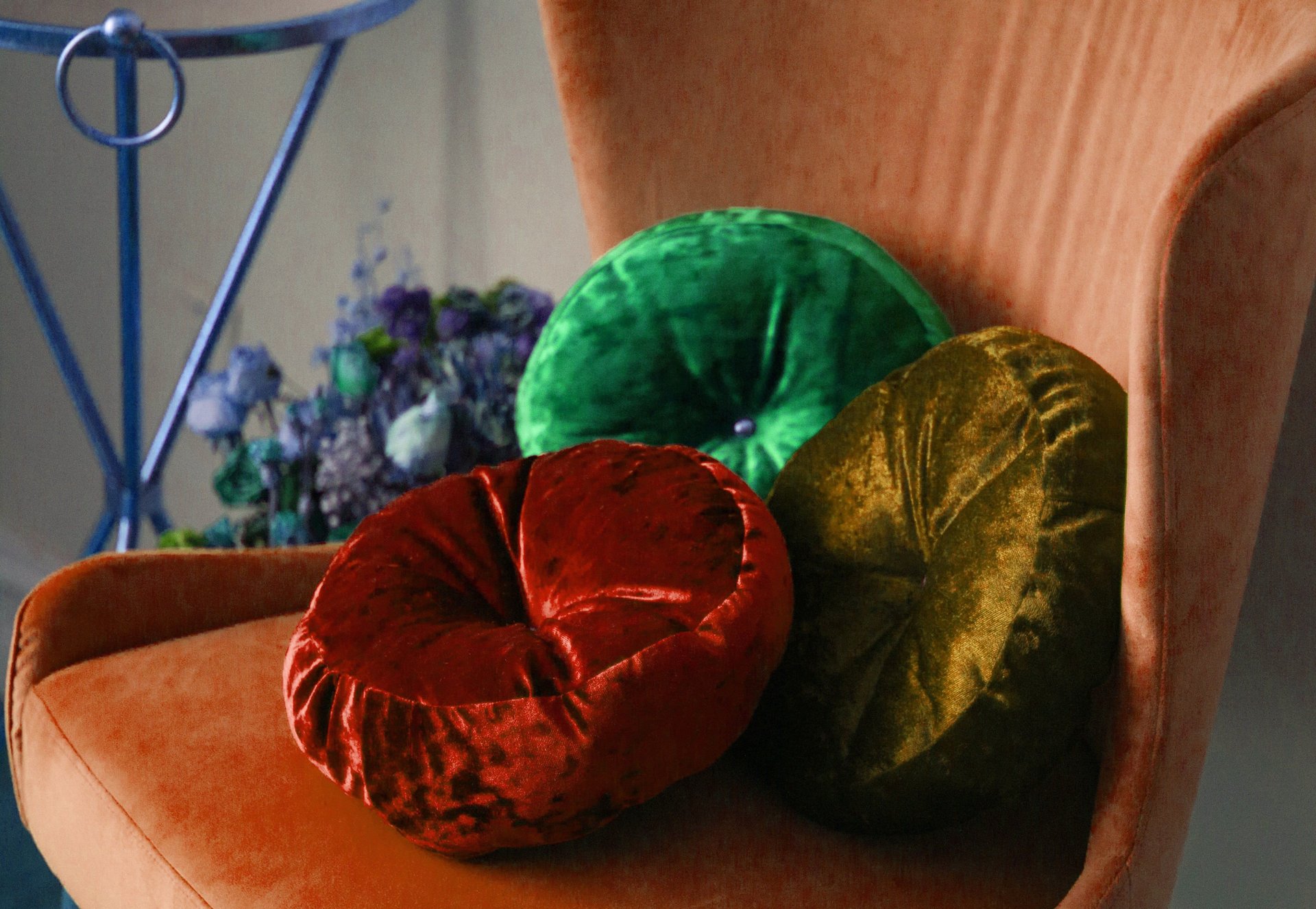 Rust-colored chair with red, green, and olive velvet cushions.
